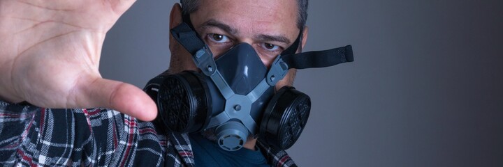 Adult white man in plaid blouse with gas protection mask looking suspiciously