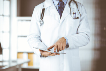 Male doctor using tablet computer in clinic, close-up. Perfect medical service in hospital. Medicine and healthcare concept