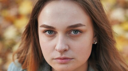 Portrait of a young and beautiful girl against a background of yellow leaves. Face close up.