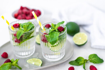 Mojito cocktail with lime, raspberry and mint in a glass. Fresh summer cocktail. Summer mojito