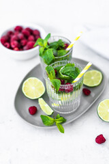 Mojito cocktail with lime, raspberry and mint in a glass. Fresh summer cocktail. Summer mojito