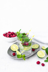 Mojito cocktail with lime, raspberry and mint in a glass. Fresh summer cocktail. Summer mojito