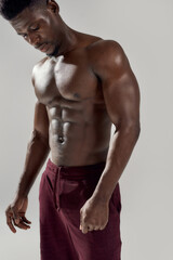 Fototapeta na wymiar Great body. Cropped shot of muscular african american man showing his naked torso while posing shirtless isolated over grey background. Sports, workout, bodybuilding concept