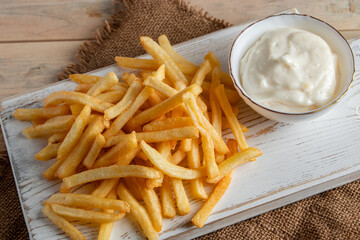 Hot golden french fries with sauce on wooden background. Homemade rustic food.