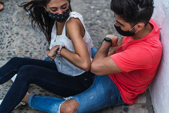 Pareja joven  sentada saludandose con los codos