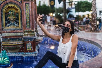 Chica joven en fuente de pueblo descansando y tomando selfies