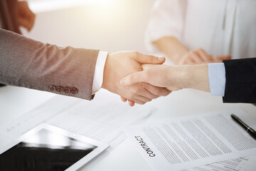 Business people shaking hands finishing contract signing in sunny office, close-up. Handshake and marketing