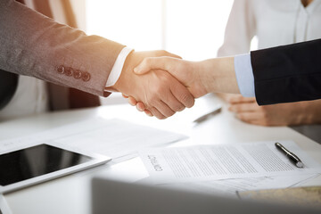 Business people shaking hands finishing contract signing in sunny office, close-up. Handshake and marketing