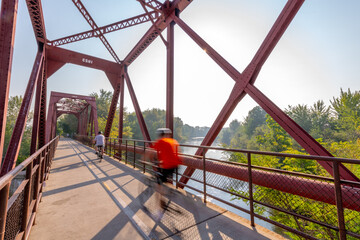 Motion blur bicyclers cross a bridge over the Boise River