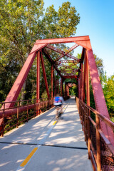Single bicycler with a pack crosses a bridge that leads over the Boise river