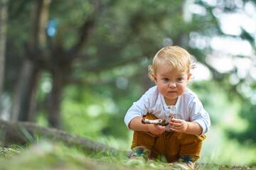 curious little child sitting in the forest studying and looking at different objects in the soil