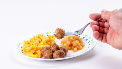 Meatball stabbed with a fork over a Macaroni and cheese dinner