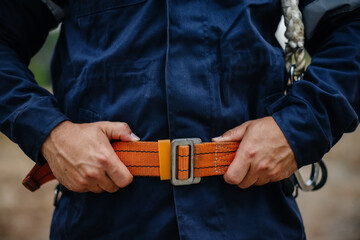 Hands and belt of a carpenter worker in close-up in work clothes and with a belt. Energy
