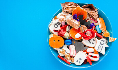 Halloween Jack o Lantern candy bowl with candy and halloween cookies Trick or Treat on blue background