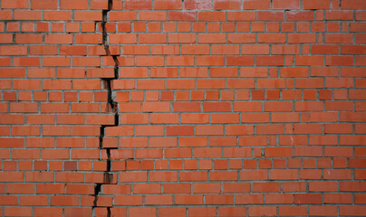 A large crack in the red brick wall.