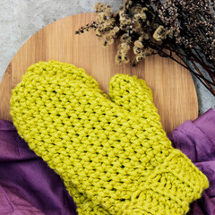  Light green handmade knitted mittens on a purple fabric and wood. Rustic style.High quality photo