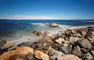 Rocks and slow motion ocean wave at Rye Harbor State Park, Portsmouth NH, USA. The park affords scenic views of the Atlantic Ocean, the Isles of Shoals, and Rye Harbor, also called Ragged Neck.
