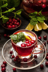 Fruit tea in glass teapot on dark background, selective focus