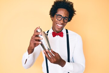Handsome african american bartender man with afro hair preparing cocktail mixing drink with shaker...