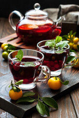 Glass cups and tea pot with berry  tea  on  wooden  background