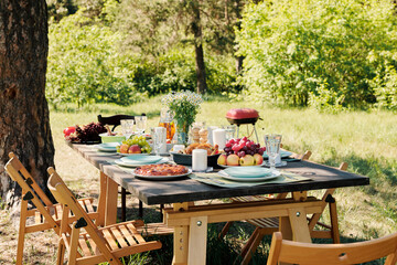 Group of chairs surrounding wooden served festive table with homemade food