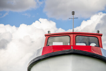 Front view on red motor boat bow and windows. Blue cloudy sky background.