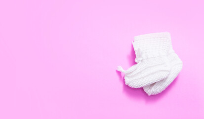 Top view of baby knitted shoes on a pink background. Flat lay small children's shoes with copy space.