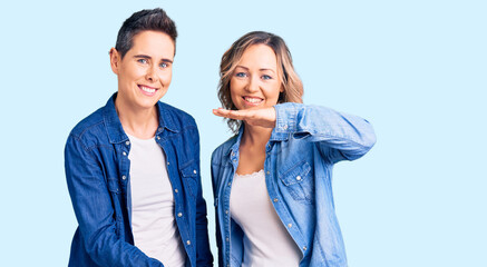 Couple of women wearing casual clothes gesturing with hands showing big and large size sign, measure symbol. smiling looking at the camera. measuring concept.