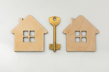 on a white background two houses and a key of gold color. Photo top view, horizontal, close-up. Concept - real estate, real estate purchase, ownership.