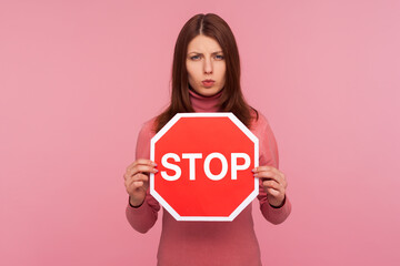 Concerned worried woman holding stop sign in hands, warning about compliance with rules, traffic...