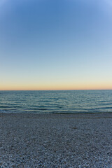 Orizzonte con tramonto e spiaggia piena di sassi