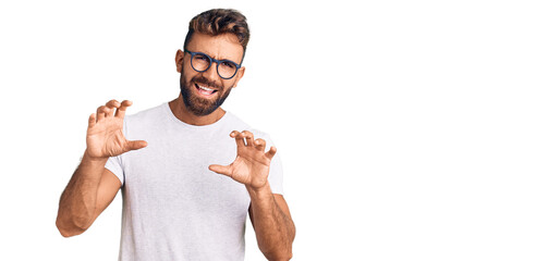 Young hispanic man wearing casual clothes and glasses smiling funny doing claw gesture as cat,...