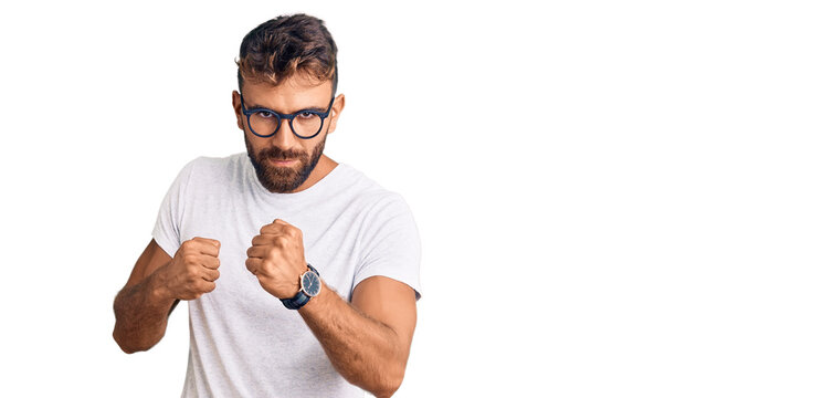 Young hispanic man wearing casual clothes and glasses ready to fight with fist defense gesture, angry and upset face, afraid of problem