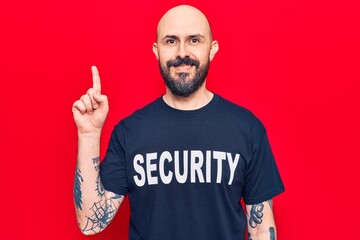 Young handsome man wearing security t shirt surprised with an idea or question pointing finger with happy face, number one