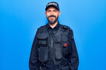 Young handsome man wearing police uniform looking positive and happy standing and smiling with a confident smile showing teeth