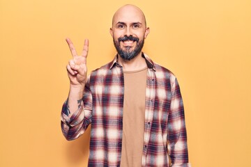 Fototapeta premium Young handsome man wearing casual clothes smiling with happy face winking at the camera doing victory sign. number two.