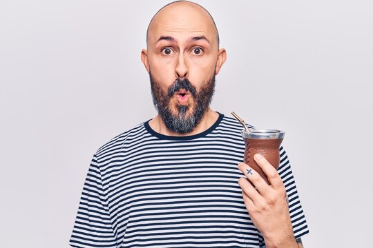 Young handsome man drinking mate infusion scared and amazed with open mouth for surprise, disbelief face