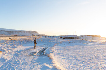 A tourist guy walks through a field in Iceland in winter. Enjoys the beauty of winter nature landscapes.