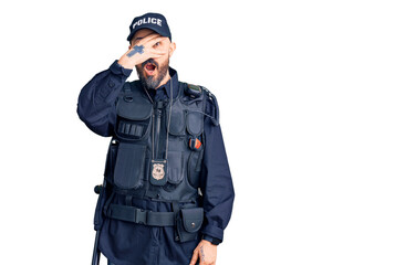 Young handsome man wearing police uniform peeking in shock covering face and eyes with hand, looking through fingers with embarrassed expression.