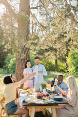 Three multicultural couples clinking with glasses of wine over served table