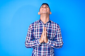 Young handsome latin man wearing casual clothes begging and praying with hands together with hope expression on face very emotional and worried. begging.