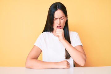 Young caucasian woman sitting at the desk wearing casual white tshirt feeling unwell and coughing as symptom for cold or bronchitis. health care concept. - obrazy, fototapety, plakaty