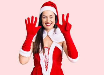 Young beautiful caucasian woman wearing santa claus costume showing and pointing up with fingers number eight while smiling confident and happy.