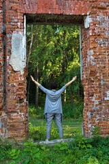 woman with raised arms up in the opening of brick wall