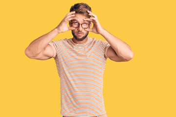 Fototapeta na wymiar Young caucasian man wearing casual clothes and glasses trying to open eyes with fingers, sleepy and tired for morning fatigue