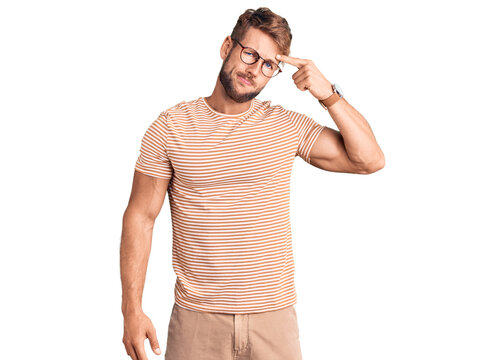 Young caucasian man wearing casual clothes and glasses pointing unhappy to pimple on forehead, ugly infection of blackhead. acne and skin problem