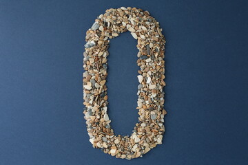 The number zero is lined with small pebbles on a blue background