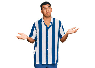 Young arab man wearing casual clothes clueless and confused expression with arms and hands raised. doubt concept.