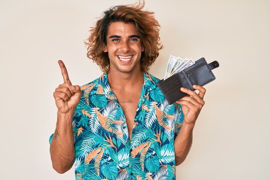 Young hispanic man holding leather wallet smiling happy pointing with hand and finger to the side