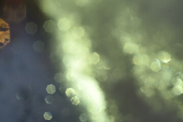 Abstract glitter bokeh on black background. Image with selective focus, noise effect and toning